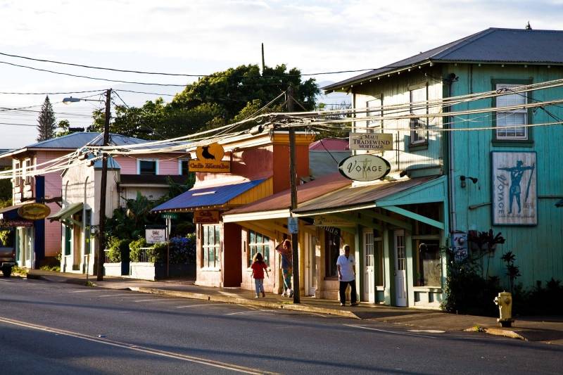 people walking down the street of colorful buildings in paia town on maui