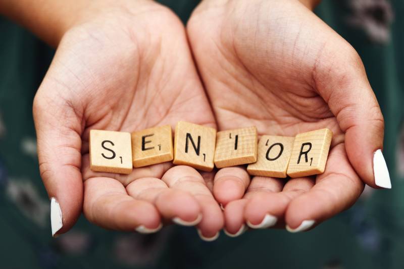ccrabble tiles in womans hands spell out :senior"