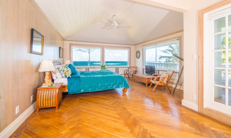 warm wood floors in bedroom with wide ocean views out the large windows
