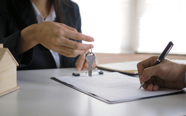 woman hands keys over to person signing contract