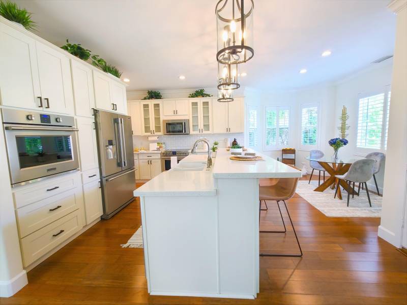 white kitchen with new appliances large island and barstools