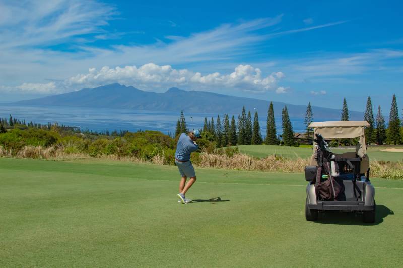 man golfing with ocean views in background