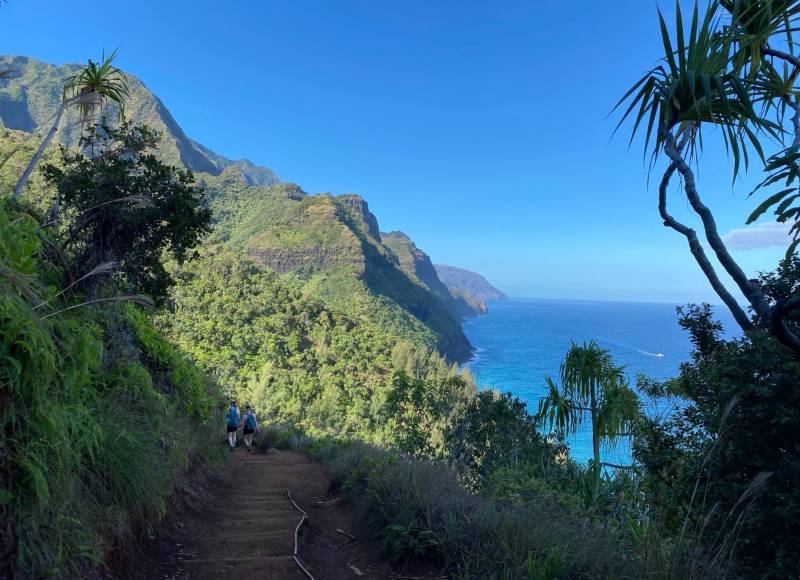 people walking on napali coast trail with ocean in background