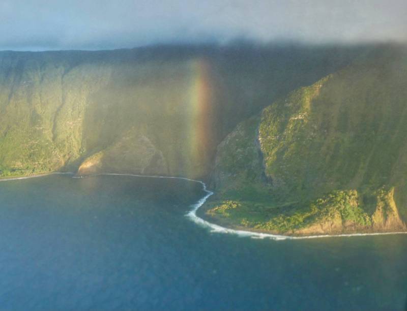 rainbow in front of maui coast cliffs