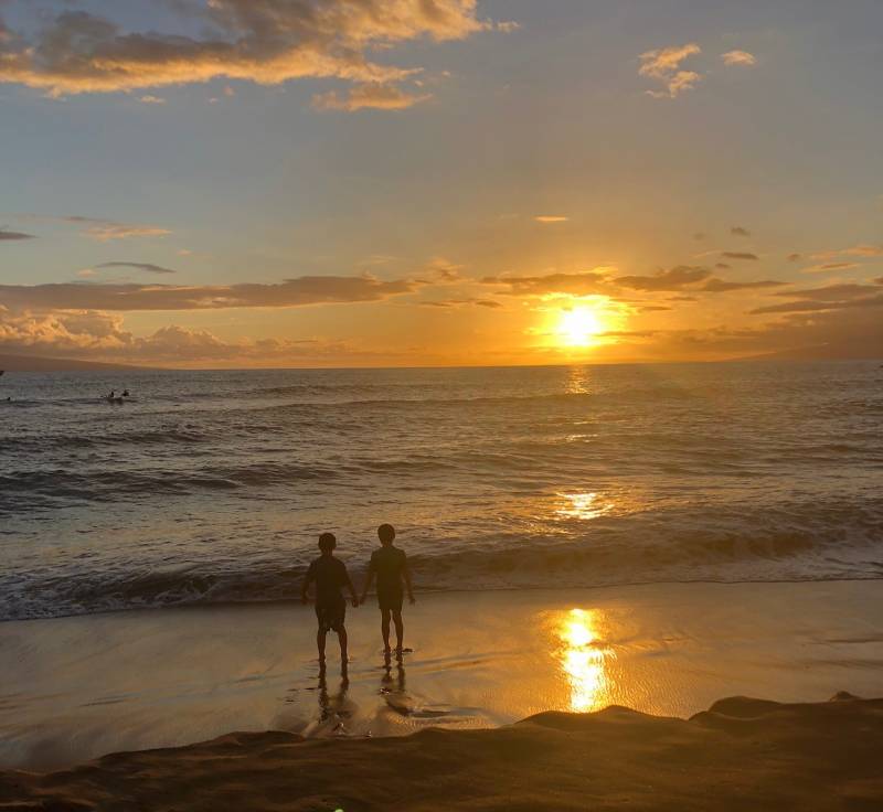 boys walking on the beach at sunset in hawaii