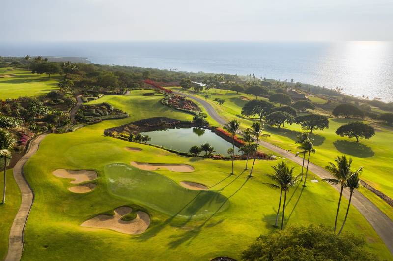 aerial view of hokulia golf course with ocean in background