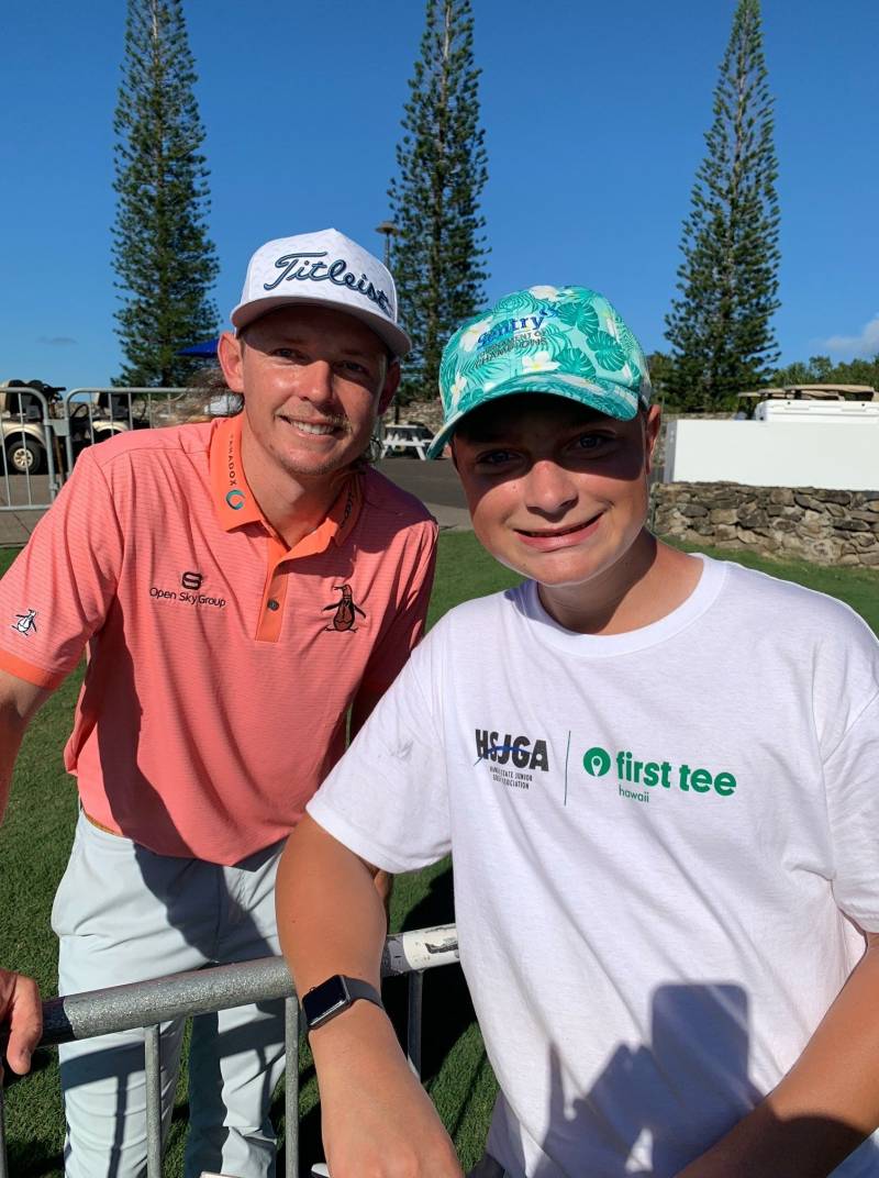 boy poses with professional golfer at golf tournament