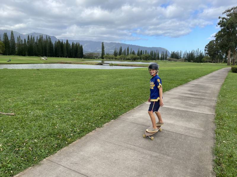 boy rides skateboard down Princeville Path