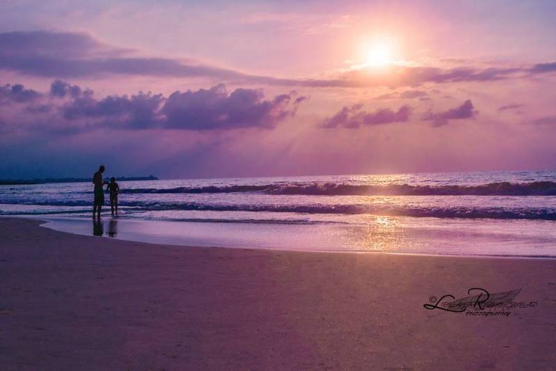 two people on the beach during purple sunset on big island hawaii