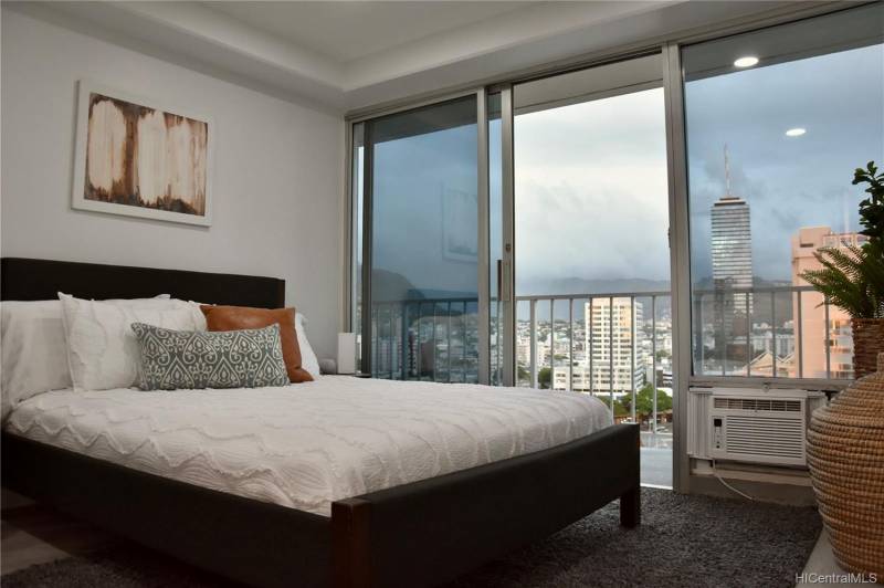 view of honolulu city and misty mountain views out of large bedroom sliding glass doors