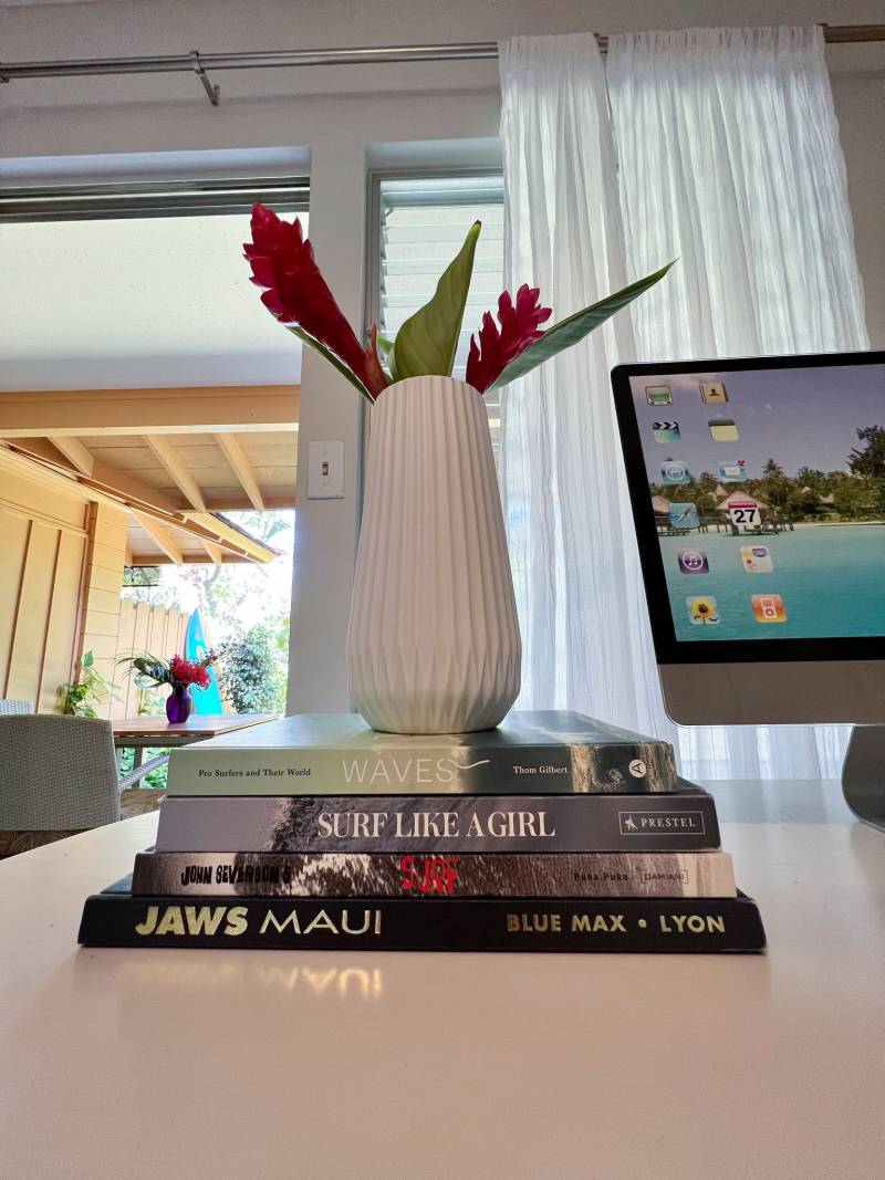 vase of tropcical plants sits on top of stack of maui and surf themed books