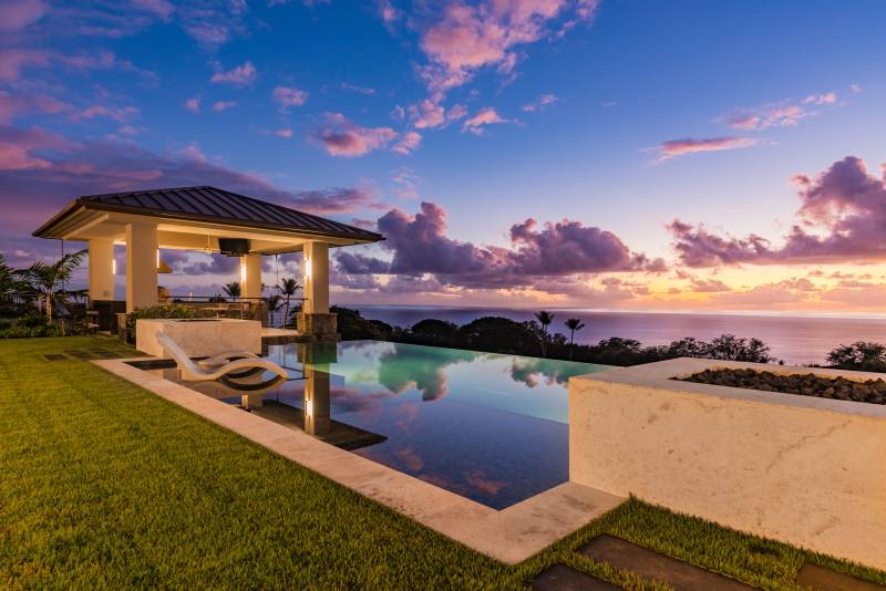 infinity edge pool extends out to ocean view at sunset at hokulia community on big island hawaii