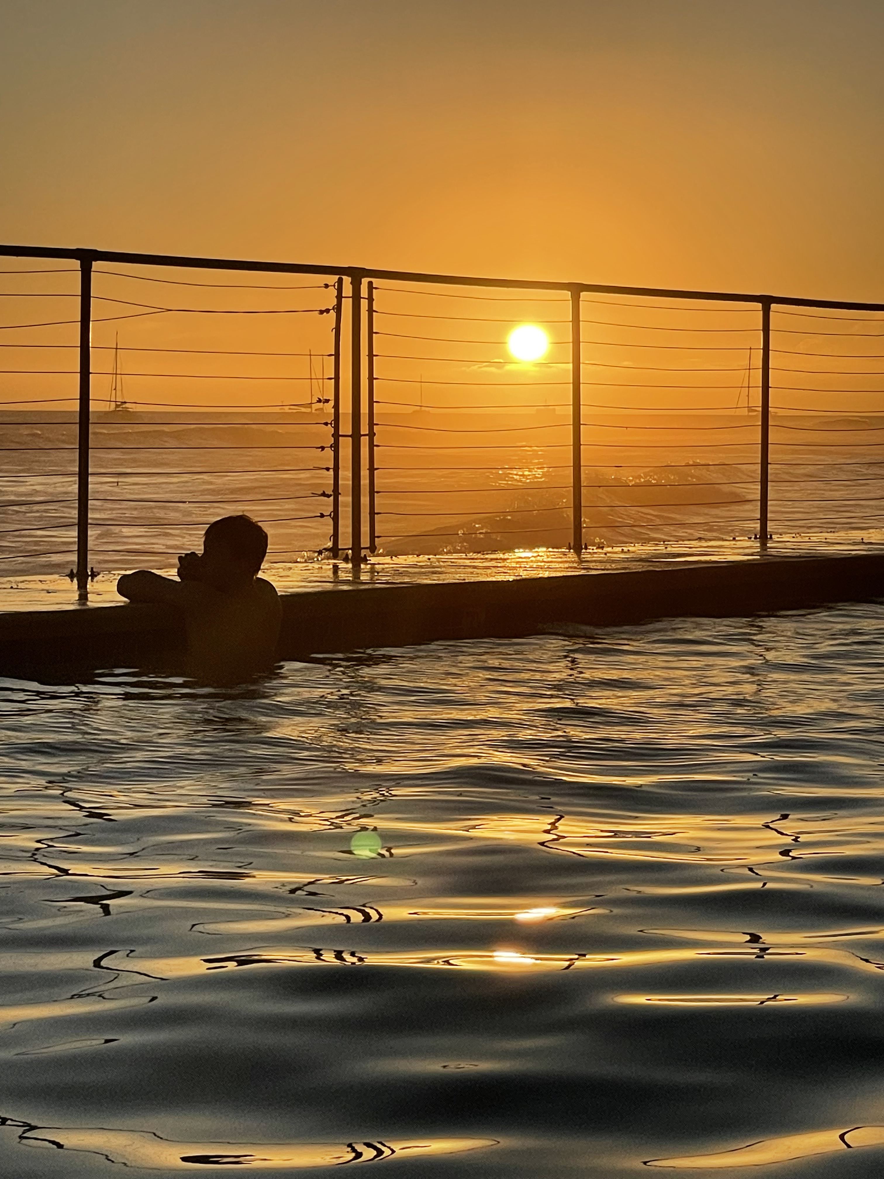 pool water appears to flow into ocean at oceanfront pool at puamana maui at sunset 