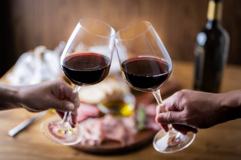 two wine glasses filled with red wine cheersing