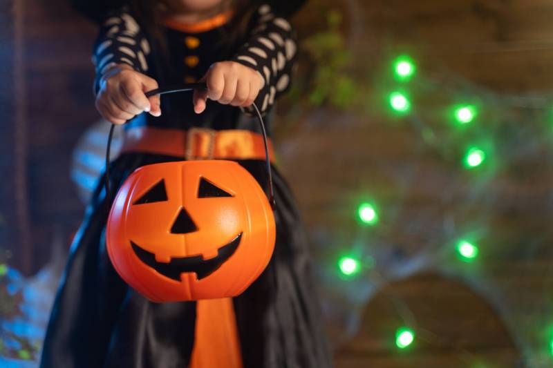 child holding out jack o lantern candy bucket for trick or treating on halloween