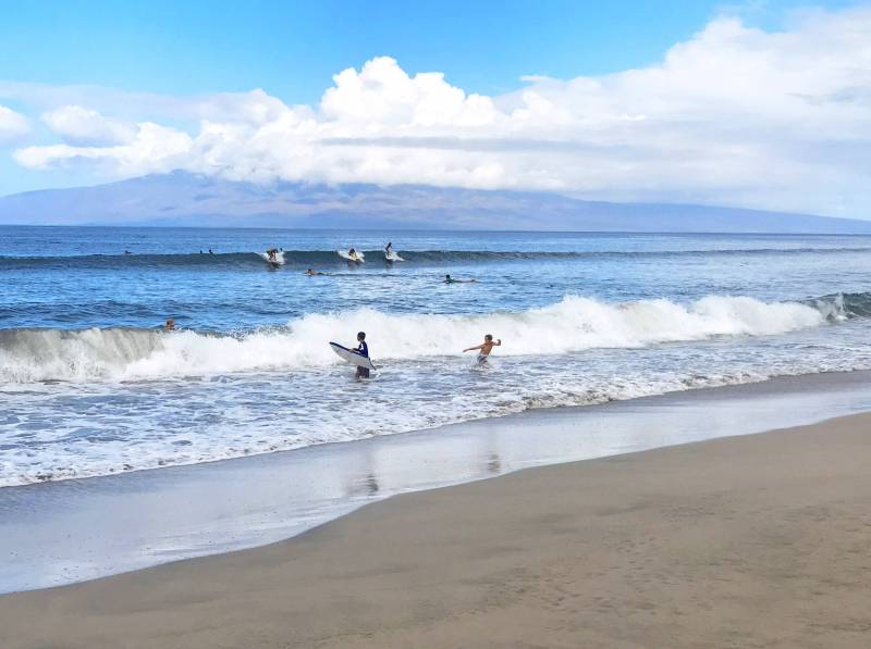 surfers on the waves out front on puamana community on maui