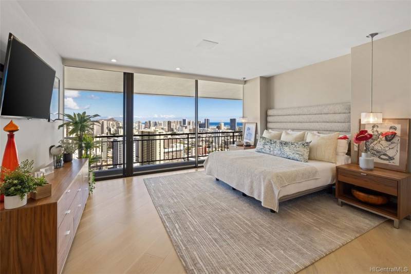 spacious bedroom with wall of windows and honolulu city views