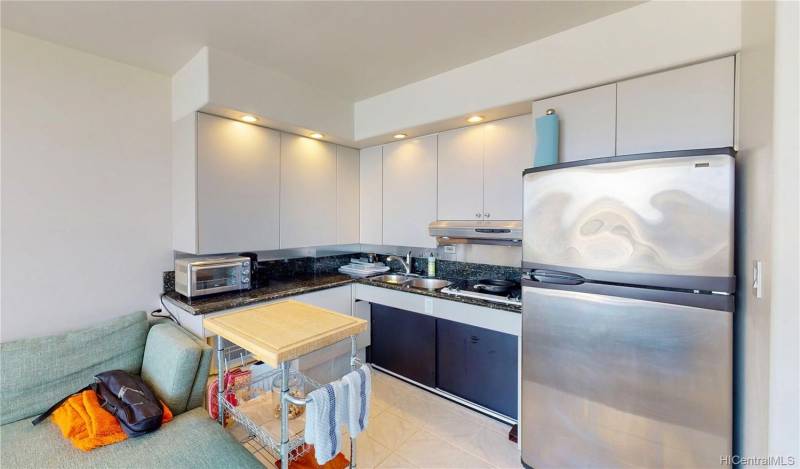 kitchen in waikiki oahu condo with white cabinets and stainless steel refridgerator