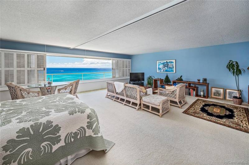 condo living room with bed and large open window with ocean views