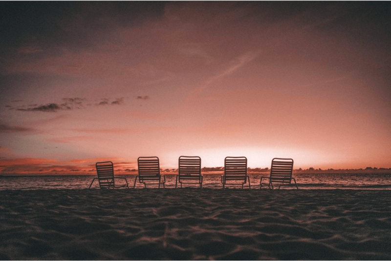 five chairs on the beach during purple sunset on big island hawaii