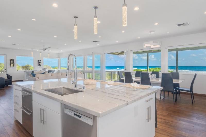 modern white kitchen island and dining room looking out to blue ocean views