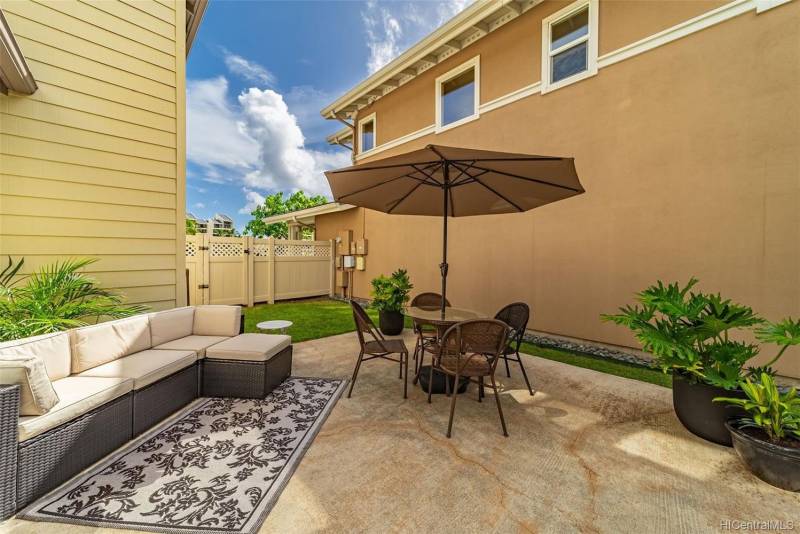 small fenced in backyard with outdoor sectional and table and chairs