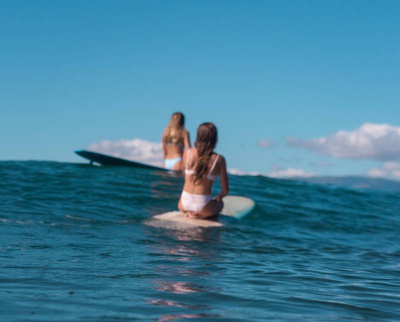 two woman sitting on surfboard in the ocean lahaina maui