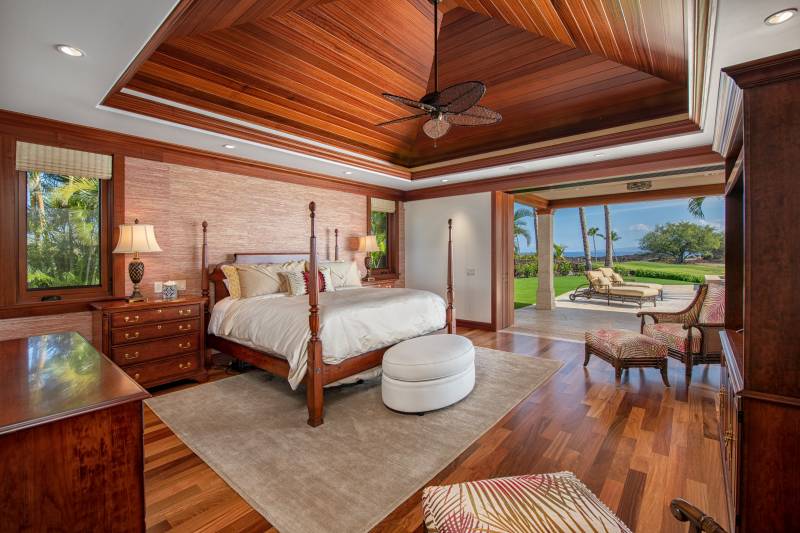 large primary bedroom with high ceilings and sliding doors that open to an ocean view seating area
