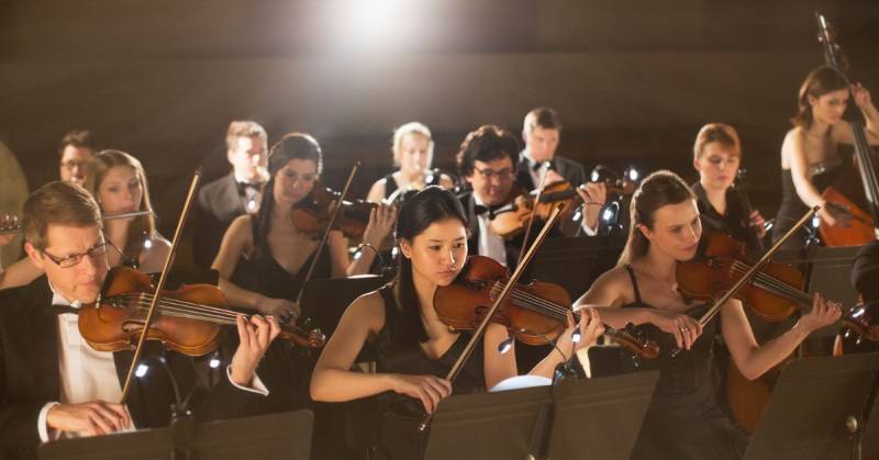 musicians playing string instruments in orchestra 