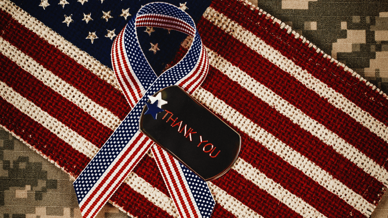 american flag ribbon with tag that says thank you laying on top of american flab