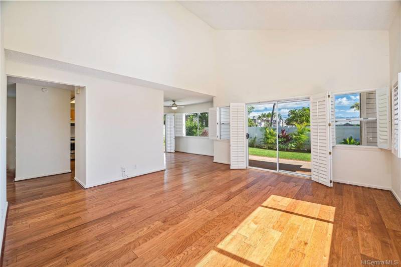 empty living room with beautiful wood floors and double doors open to backyard
