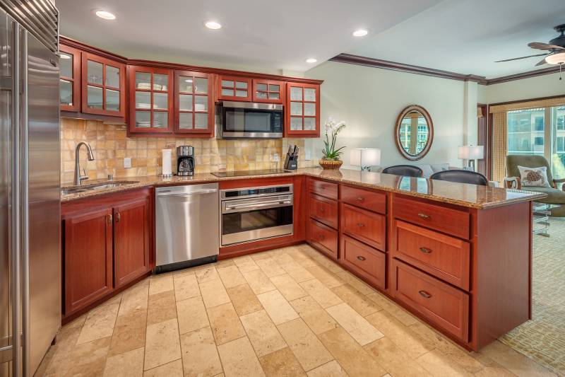 kitchen with cherry wood colored cabinets and warm tan tile floor and backsplash