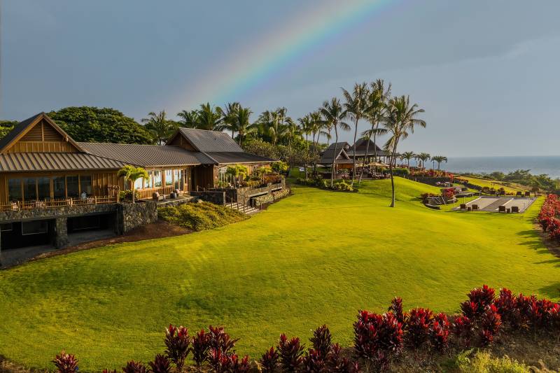 the club at hokulia with a rainbow in the sky above