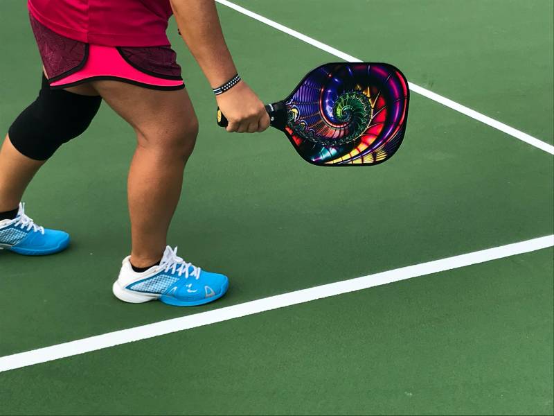 woman playing pickleball with a colorful paddle