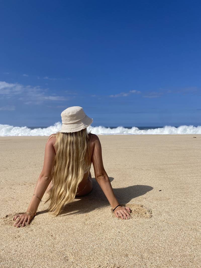 woman with long blonde hair lounging on oahu beach