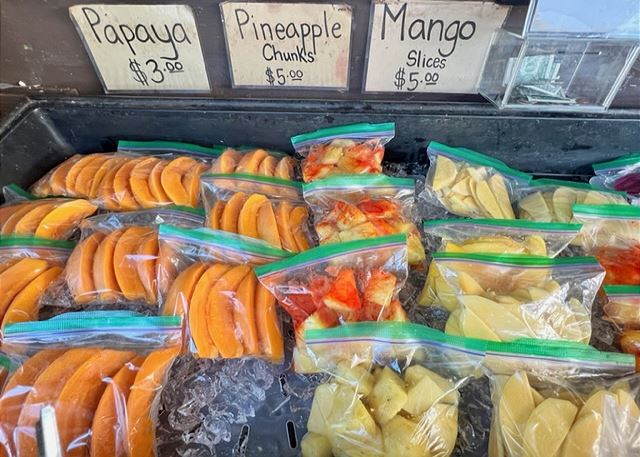 market stall with bags of fresh papaya, pineapple, and mango