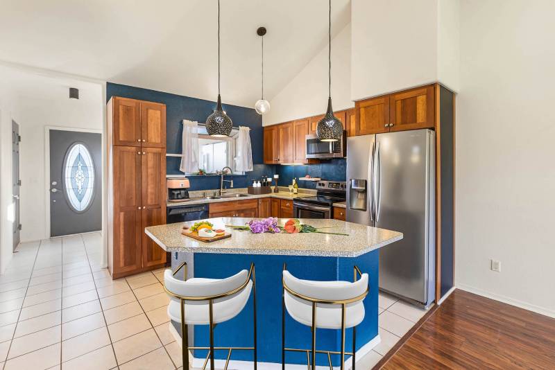 kitchen with white tile, wood cabinetry. blue painted island