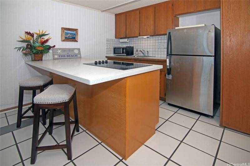 small oahu condo kitchen with white tile and wood cabinets