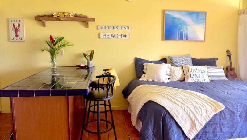 yellow walls and bed near kitchen bar in beachy studio condo on molokai