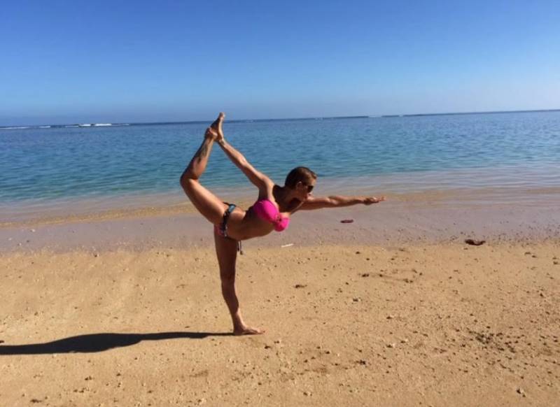 woman doing dancer pose on the beach in hawaii