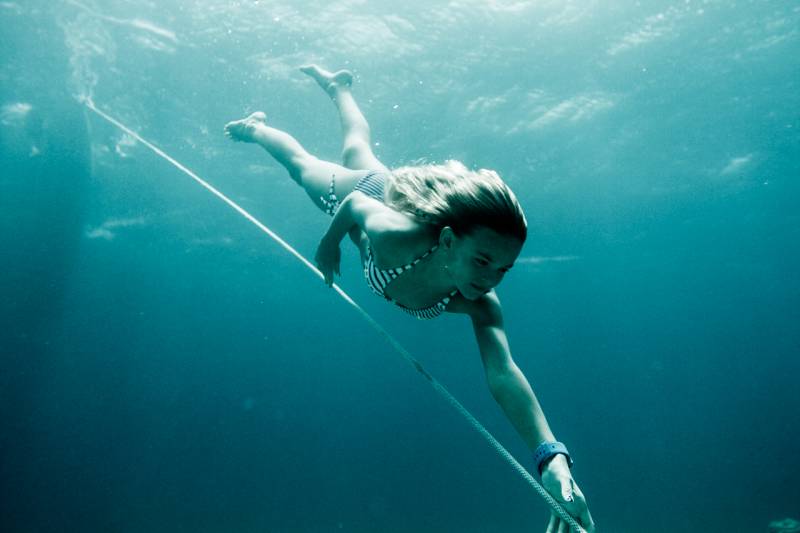 woman holding a rope while freediving in blue ocean water