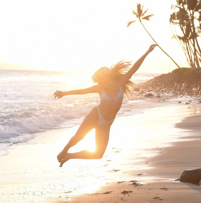 woman in bikini jumping on the beach