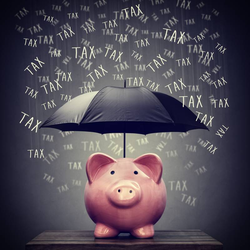 piggy bank holding umbrella with work tax raining down