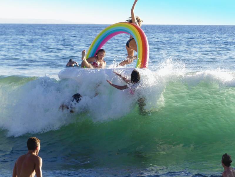 kids playing on rainbow floaty in the ocean