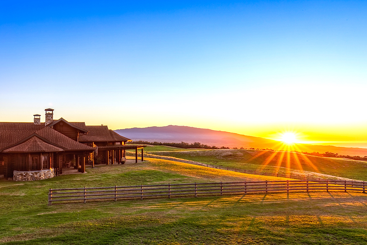 big island ranch home with sun rising over the mountain in background