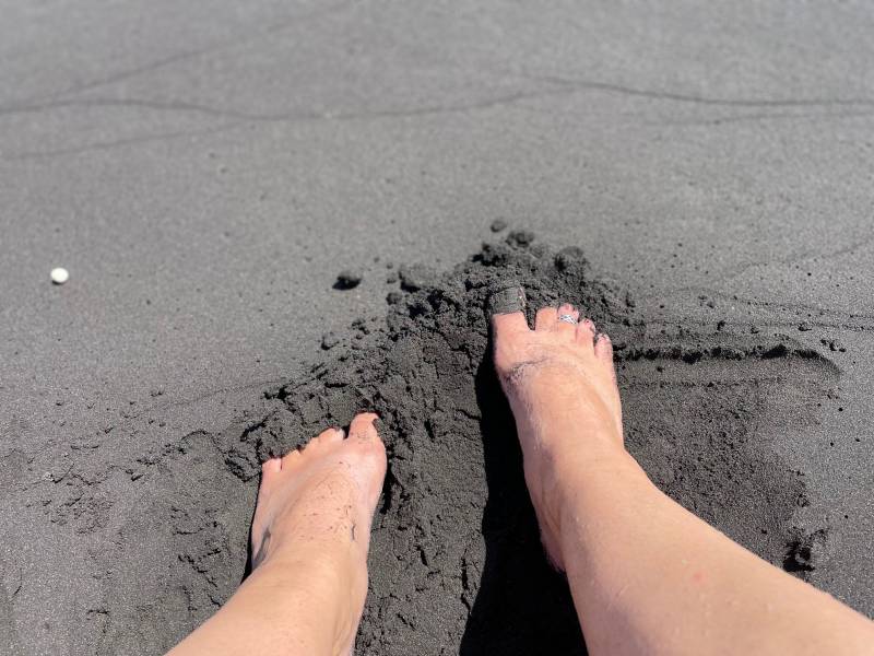 feet in soft black sand