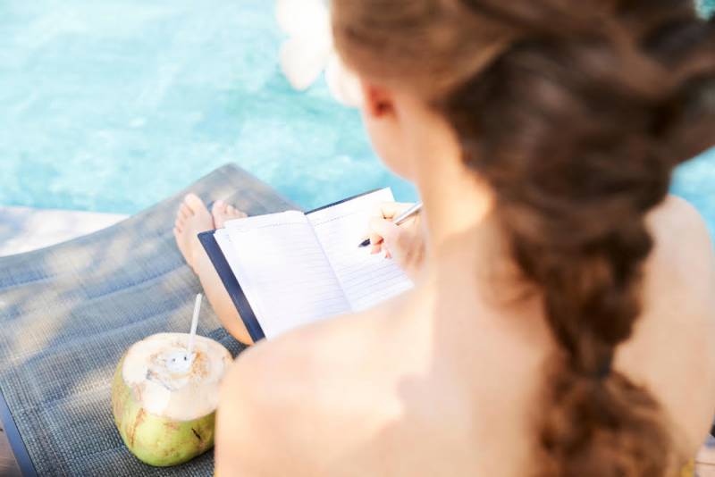 woman journaling by the pool