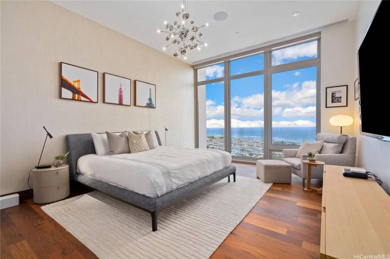 large bedroom with floor to ceiling windows let in ocean views