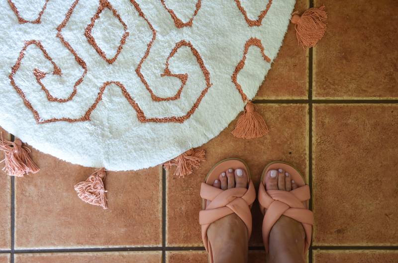 white round rug and feet in tan sandals