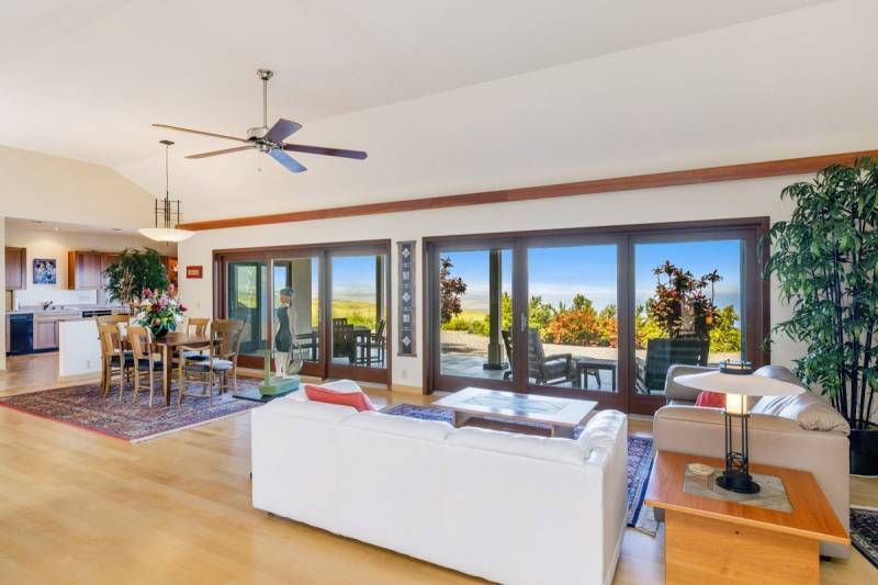 living and dining room in kohala ranch home with ocean view through large glass doors